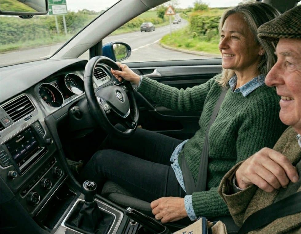 A volunteer driver at the wheel with a passenger beside her