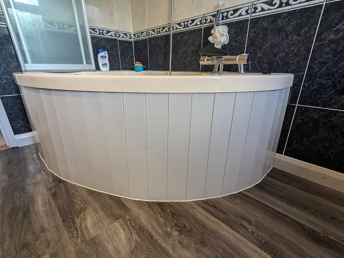 A curved bath panel in white tongue and groove