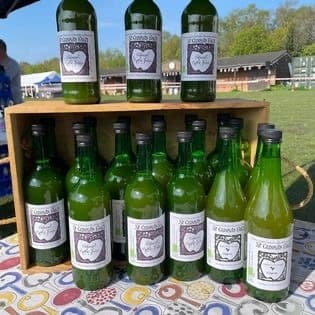 Bottles of local apple juice in a wooden crate on a stall