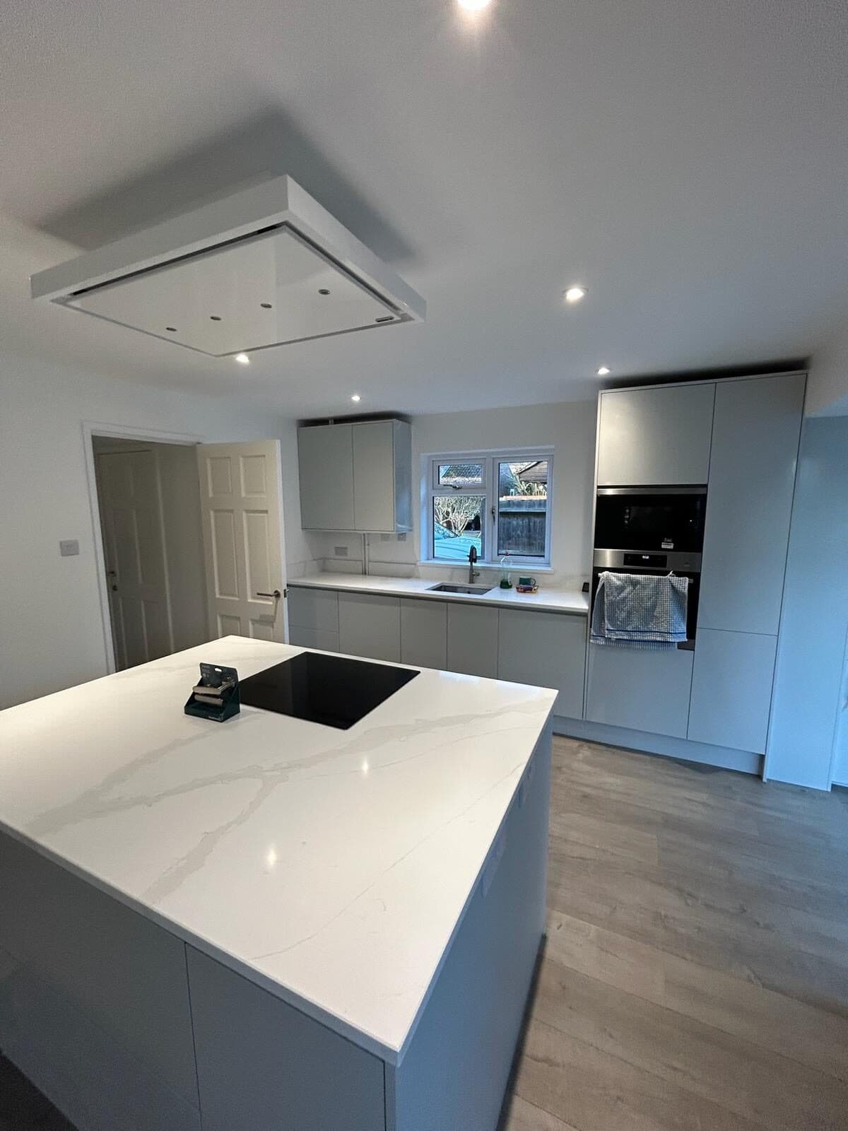 A finished kitchen with a white quartz island and grey units