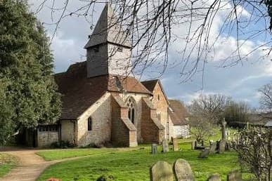 St Mary the Virgin church in early spring, its shingled spire above the churchyard, with a path running past the gravestones.